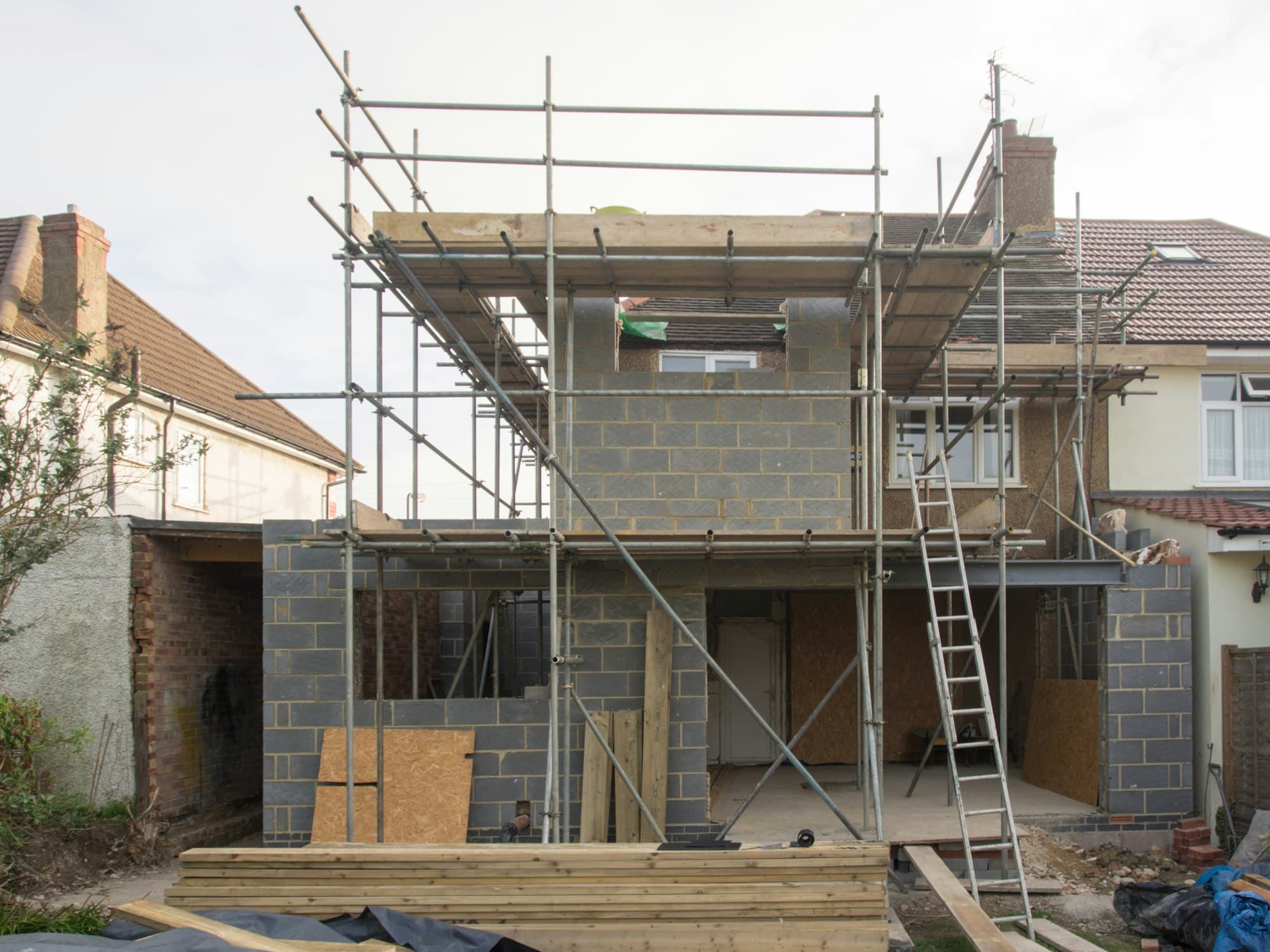 Residential building with an extension under shell construction, scaffolded